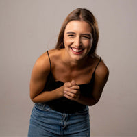 Thumbnail for Smiling woman wearing a black top and denim skirt, exuding joy and warmth, perfect for lifestyle imagery.