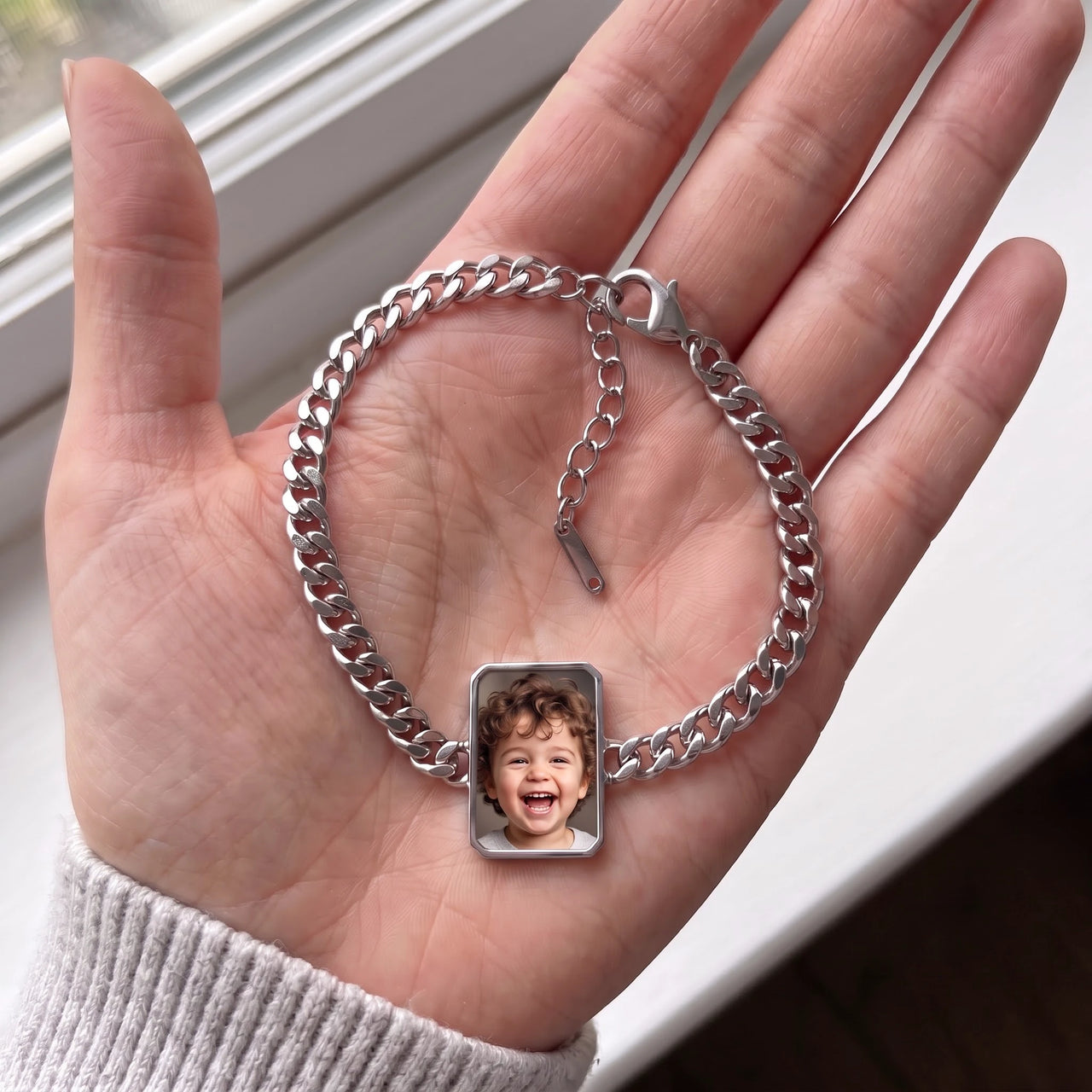 The silver cushion-cut photo bracelet in her palm, showing the lobster clasp and extension chain, with a little boy's photo | SKU: TPH-CUSB-SILVER